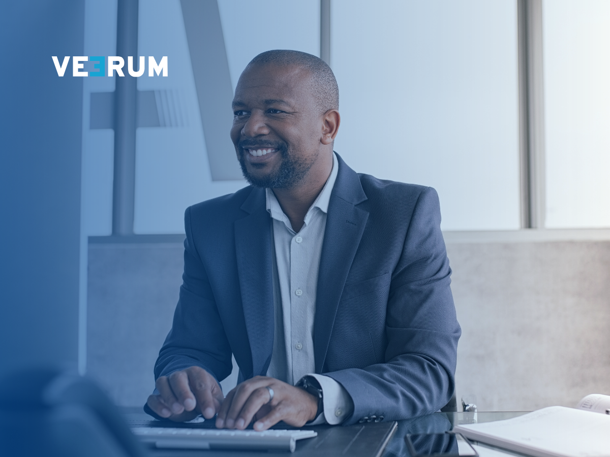 A man smiling while working on his computer, using VEERUM 3DVAULT to visualize 3D models and geospatial data.